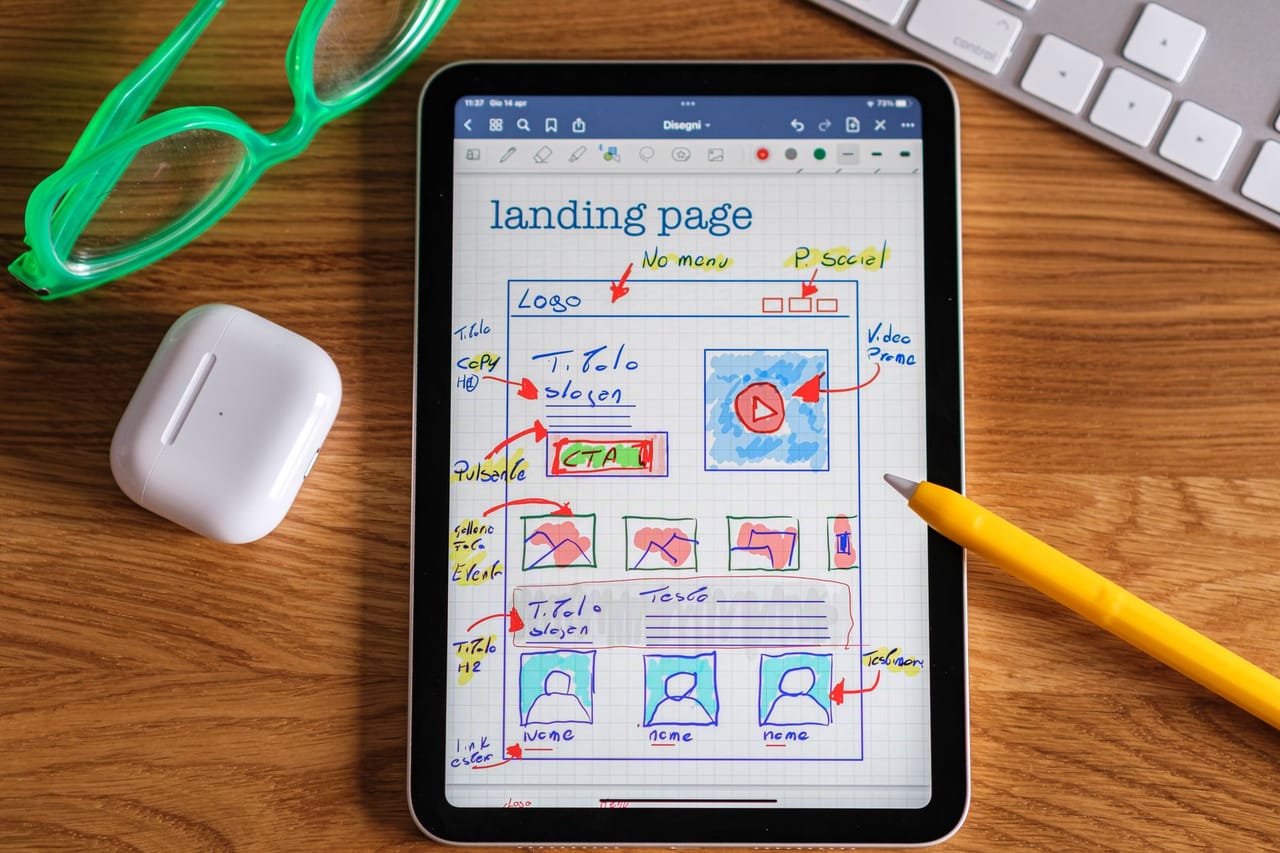 Hand-drawn wireframe of a landing page on a tablet, with notes in red and blue
